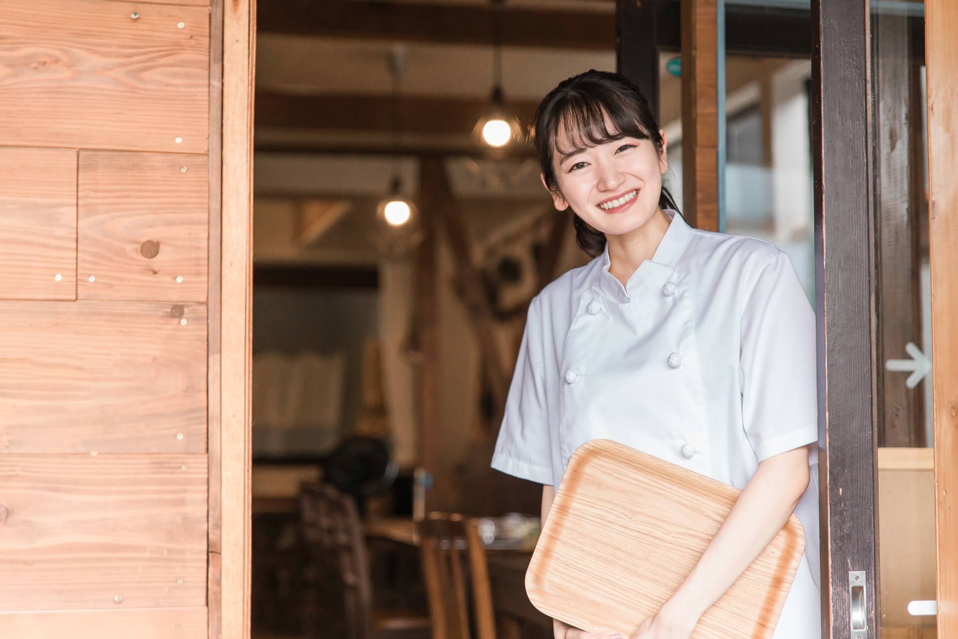 レストランで木製のまな板を持つアジアの若い女性。