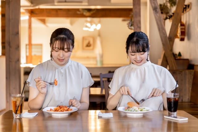 テーブルに座って食べ物を食べる2人のアジア人女性。