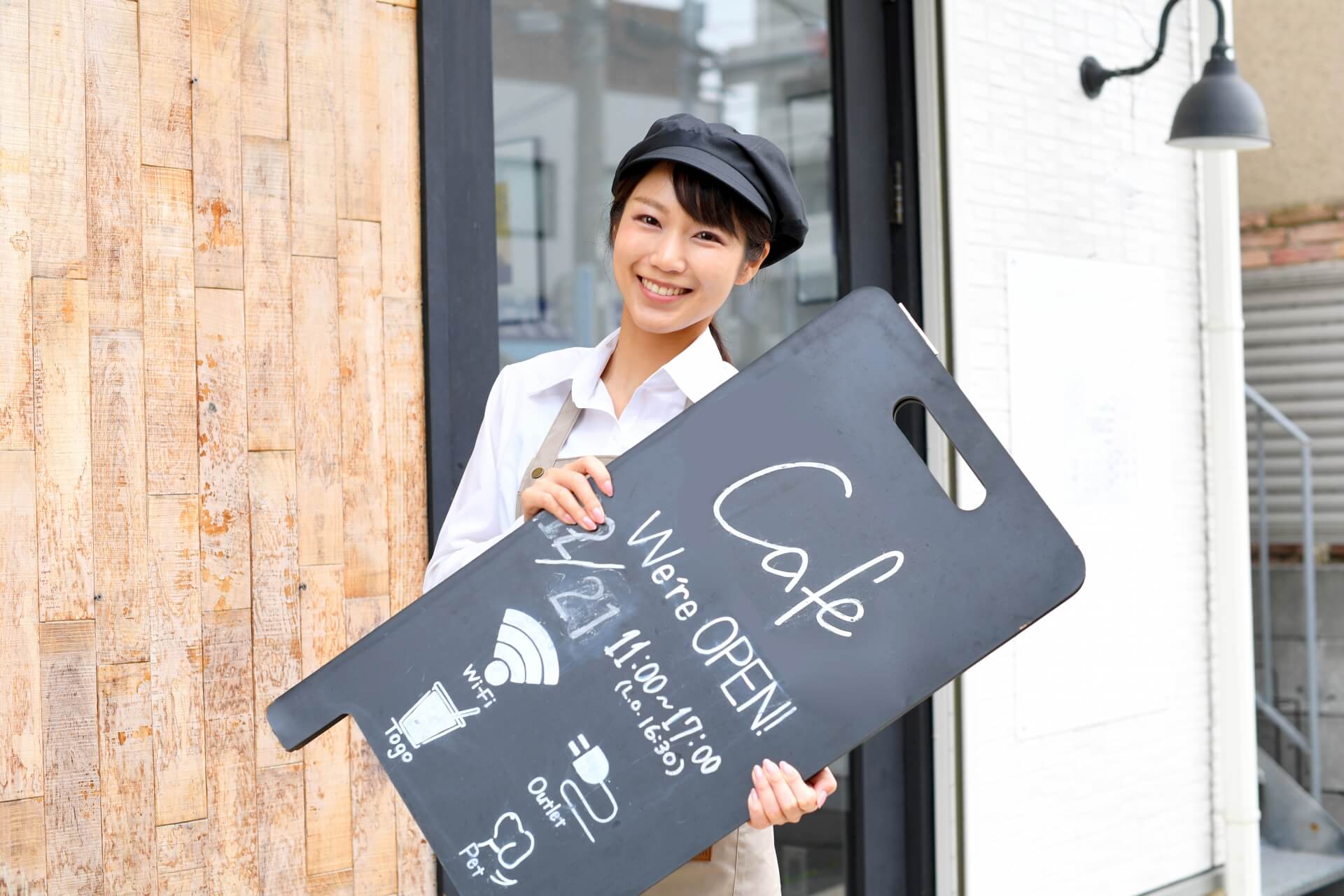 黒板看板を掲げる日本人女性。