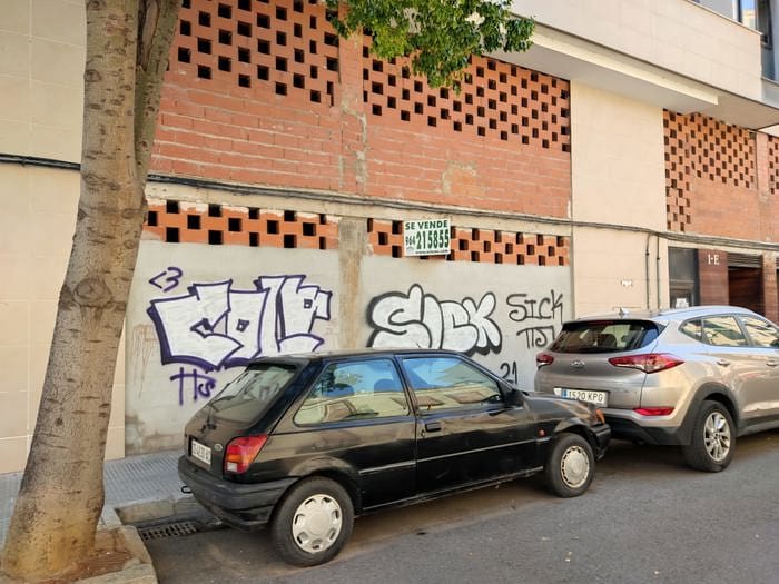 スペインにある落書きのある建物の前に駐車されているスペイン・カステリョンの商業用不動産。