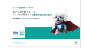 日本の広告では、スーパーヒーローの青いマントを着た小さな白い犬が「SmellSSackSSack」ボトルの横に登場しています。日本語と英語の文字でクリーンスメルのペットケアを強調し、左下にはペット消臭認定ロゴが入っています。.