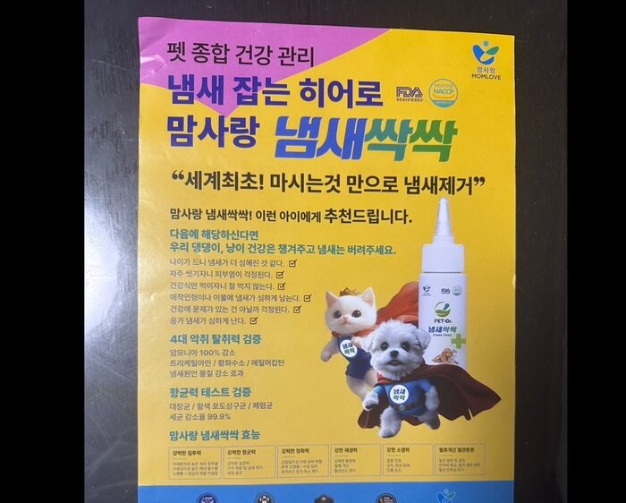 ペット用健康製品「ペットヘルスケア」の韓国の広告では、猫と犬の画像、ノズル付きの白いボトル、黄色と紫の背景に大胆なカラフルな文字、そして上部にロゴとクリーンスメル認証が表示されています。.