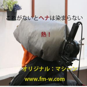 日本語の文字が重なり、オレンジ色のタオルが首を包んでいる。おそらくショートカットの最中にヘナサービスを楽しんでいるのだろう。.