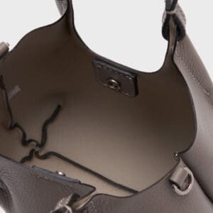 スナップボタンで開閉し、内側にステッチが見えるGIANNI CHIARINIのトープレザー製ハンドバッグ「デュア XS」の内側をクローズアップ。.