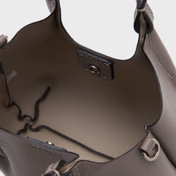 スナップボタンで開閉し、内側にステッチが見えるGIANNI CHIARINIのトープレザー製ハンドバッグ「デュア XS」の内側をクローズアップ。.