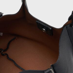 スナップボタン開閉、ドローコード付き。無地を背景に空のバッグを撮影。.